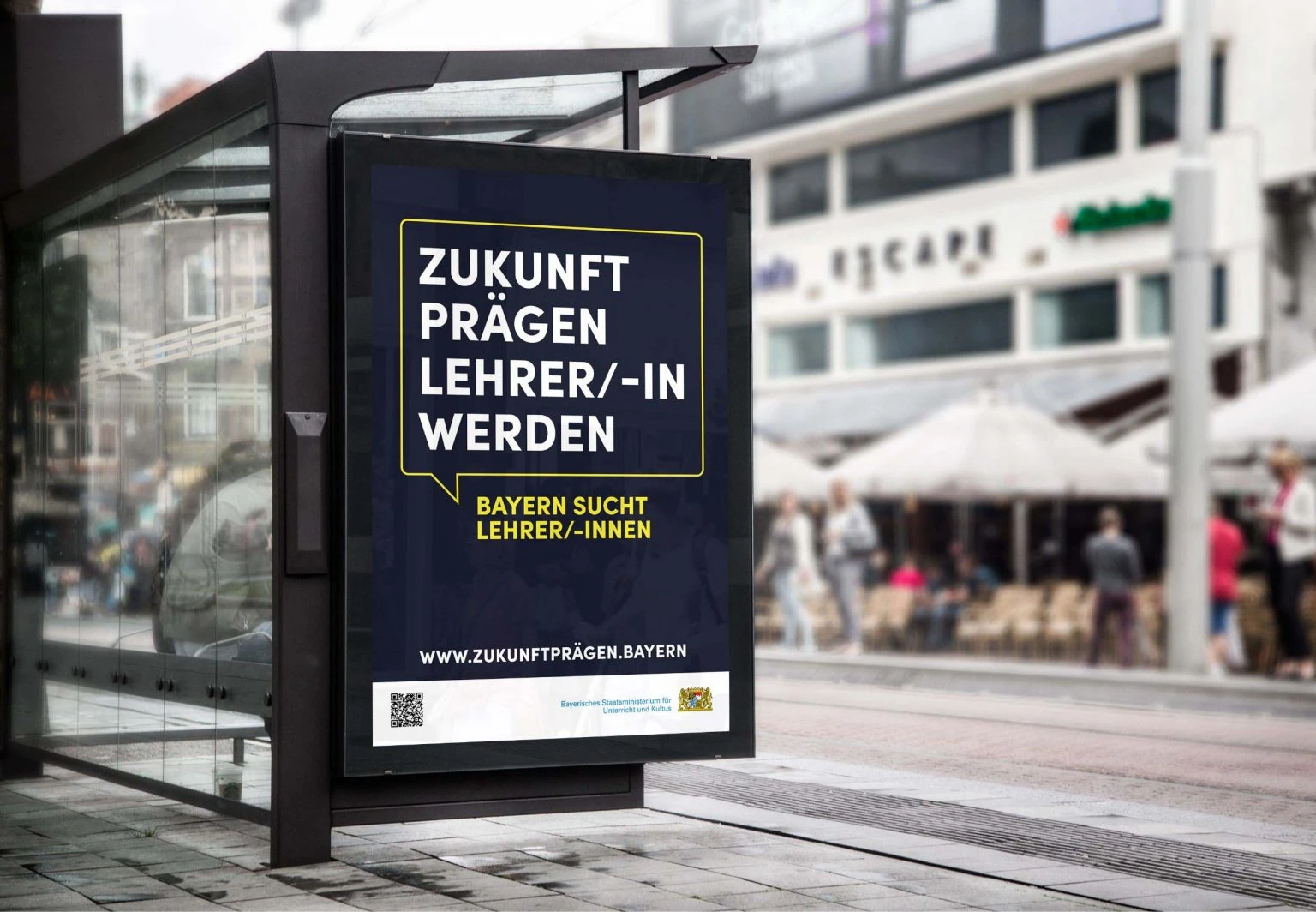 Ein blaues Plakat der Kampagne Zukunft prägen - Lehrer/-in werden hängt an einer Bushaltestelle